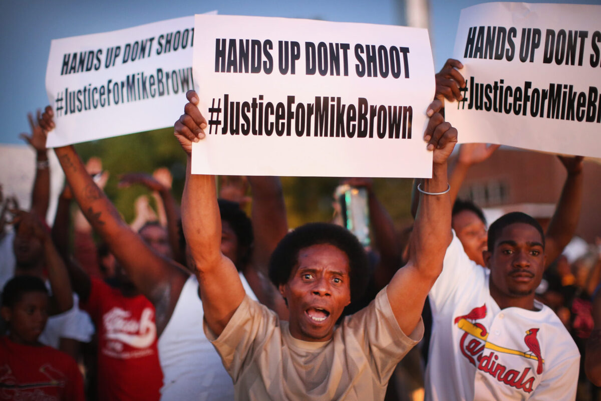 ST. LOUIS, MO - AUGUST 12: Demonstrators protest the killing of teenager Michael Brown outside Greater St. Marks Family Church while Browns family along with civil rights leader Rev. Al Sharpton and a capacity crowd of guests met inside to discuss the killing on August 12, 2014 in St Louis, Missouri. Brown was shot and killed by a police officer on Saturday in the nearby suburb of Ferguson. Ferguson has experienced two days of violent protests since the killing but, tonight the town remained mostly peaceful. (Photo by Scott Olson/Getty Images)